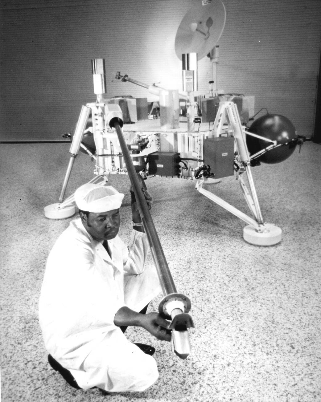Viking lander spacecraft on ground with technician in clean suit checking robotic arm