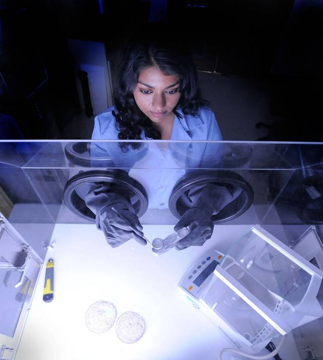 A view looking down at Nithin Abraham studies a paint sample in her laboratory.