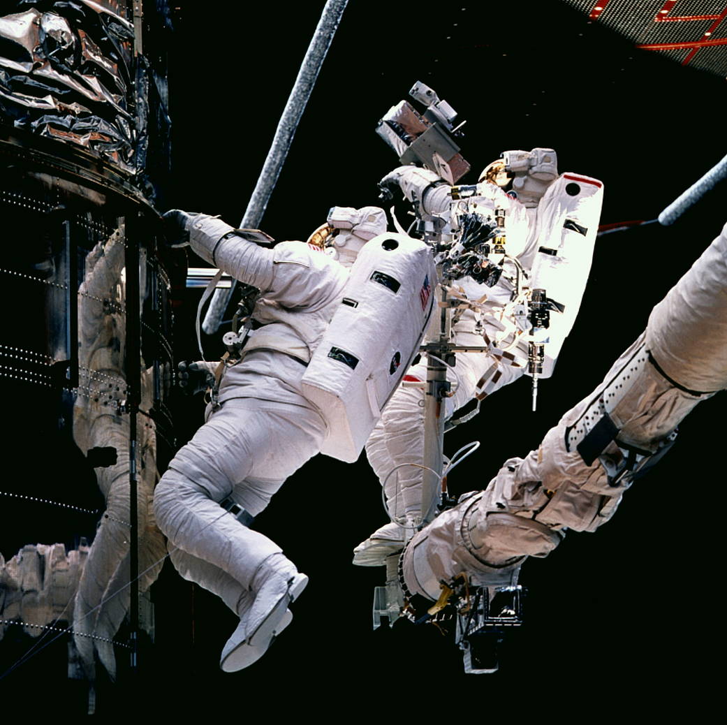 Payload Commander Mark C. Lee (left) and Mission Specialist Steven L. Smith (on RMS arm) conduct an unscheduled fifth extravehic