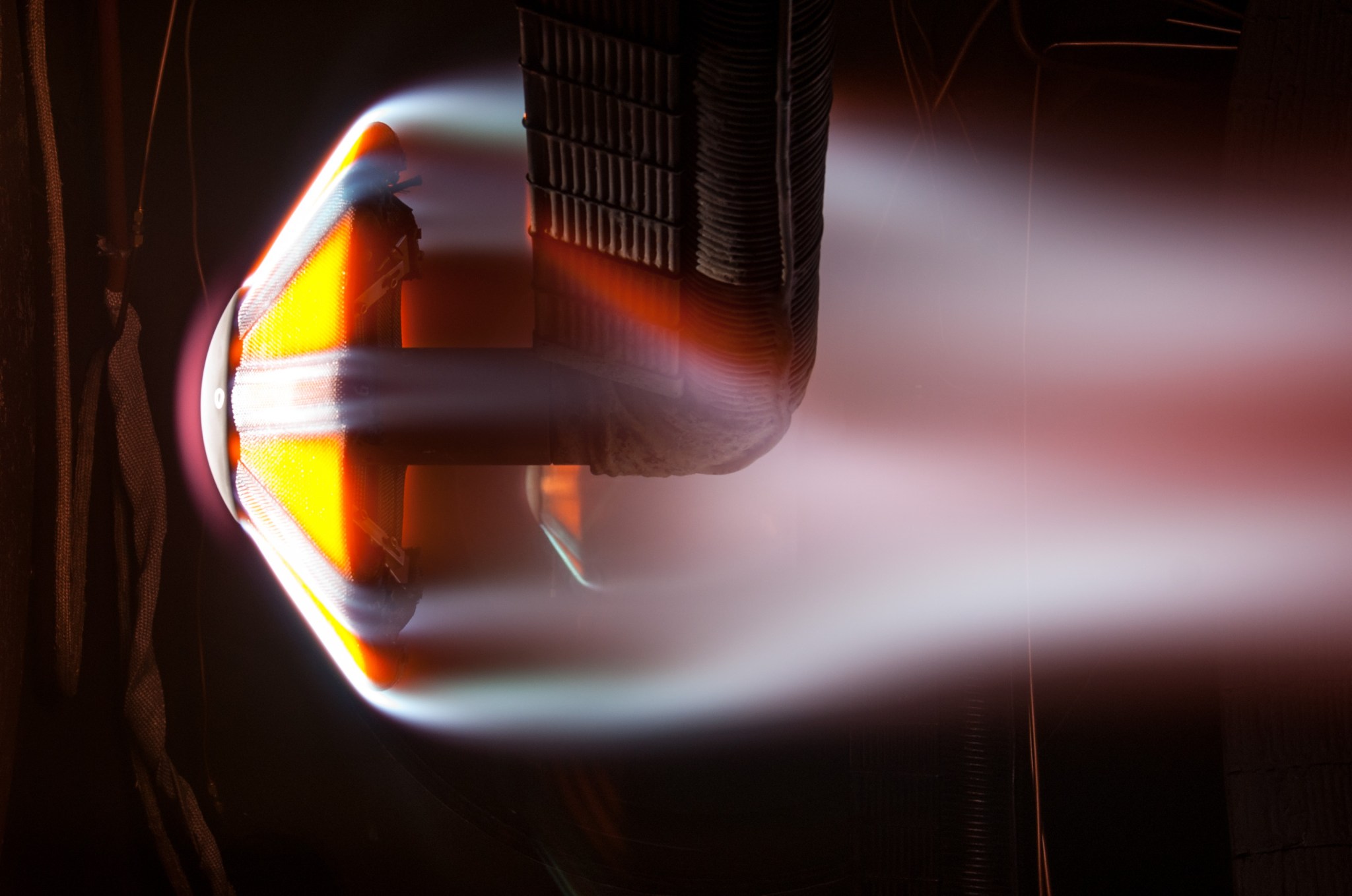 This image is from the Interactive Heating Facility ArcJet and shows the flow of extremely heated air exiting the 21-inch diameter nozzle from the left, causing a bow shock to form in front of the ADEPT test article.