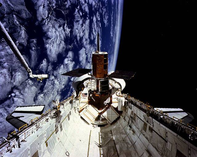 Space shuttle Challenger, mission STS-41C, is seen in space with the Earth in the background