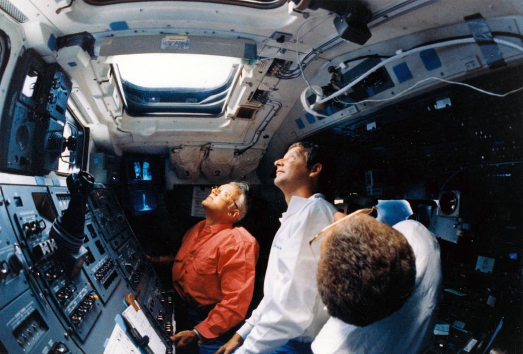 Three astronauts on space shuttle look out window