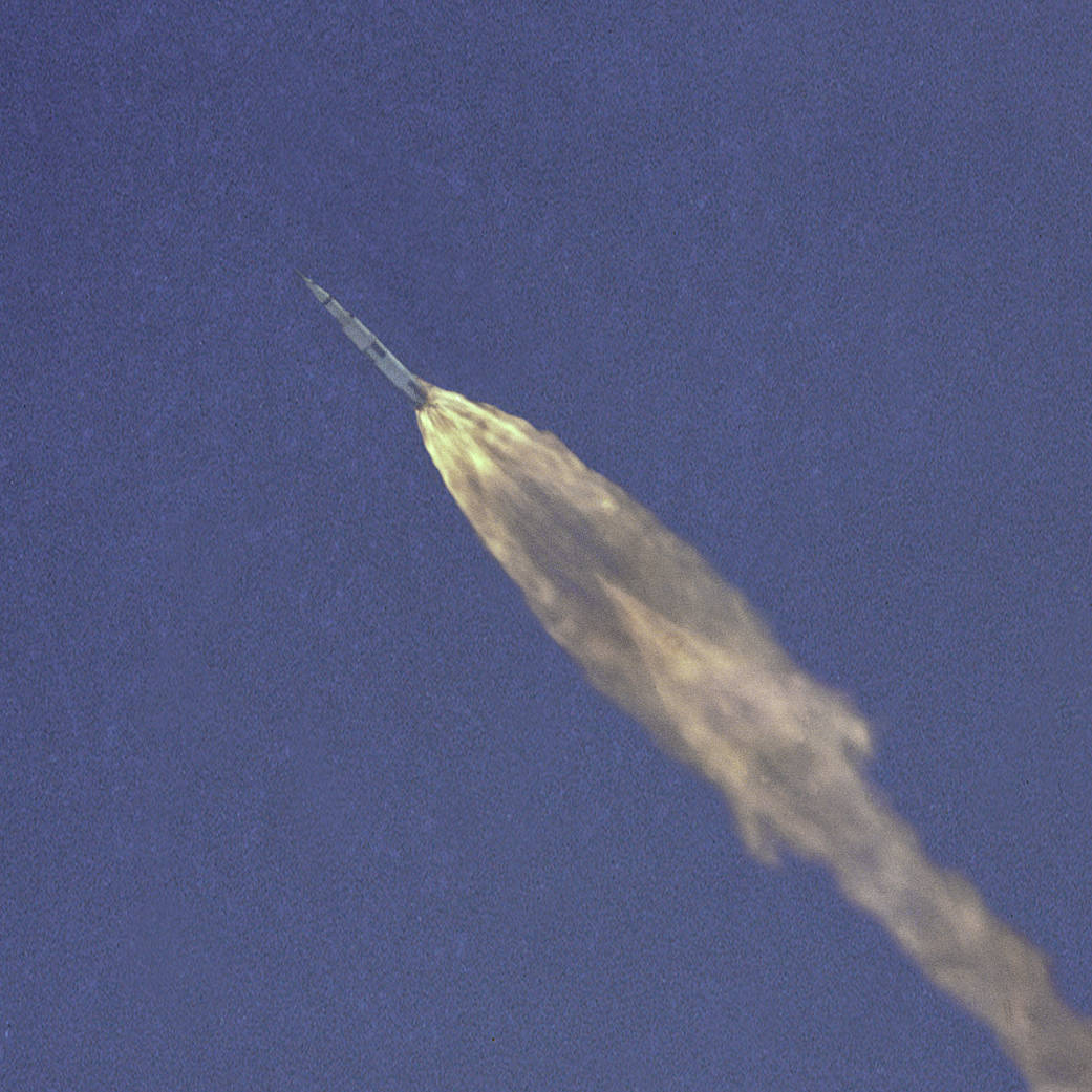 Apollo 10 Saturn rocket streaks diagonally across blue sky just after launch