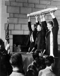 Model of Explorer 1 held up by three men at news conference