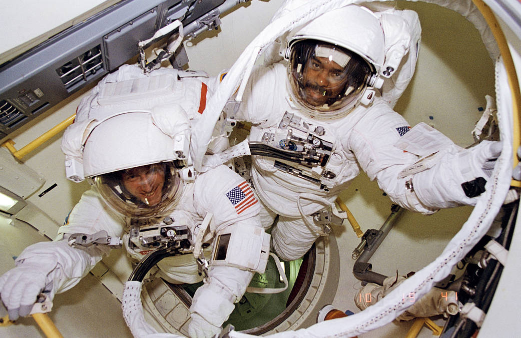 Two astronauts in spacesuits in airlock aboard shuttle Discovery