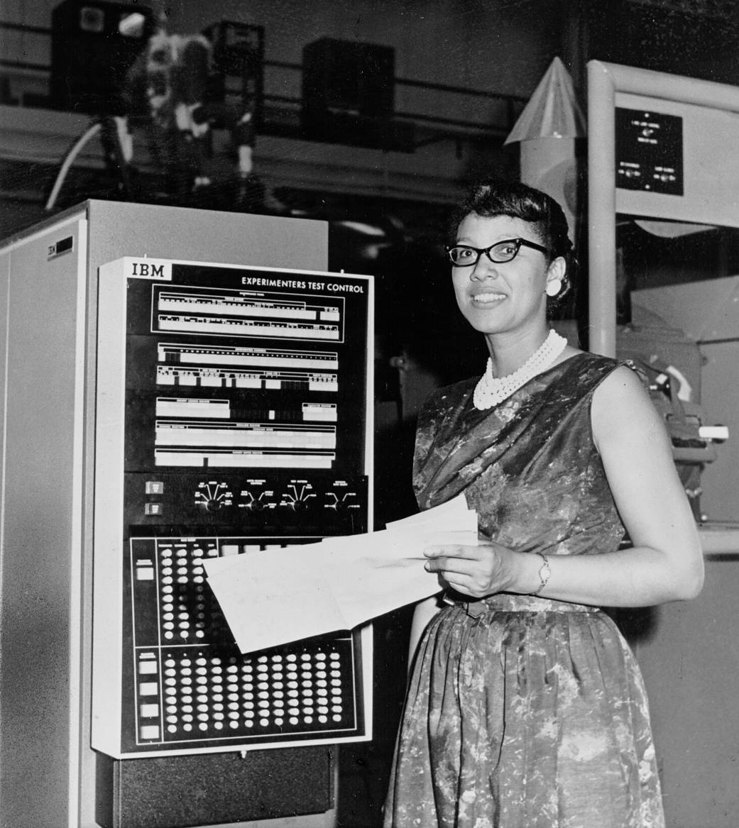 Melba Roy standing next to machine with cards