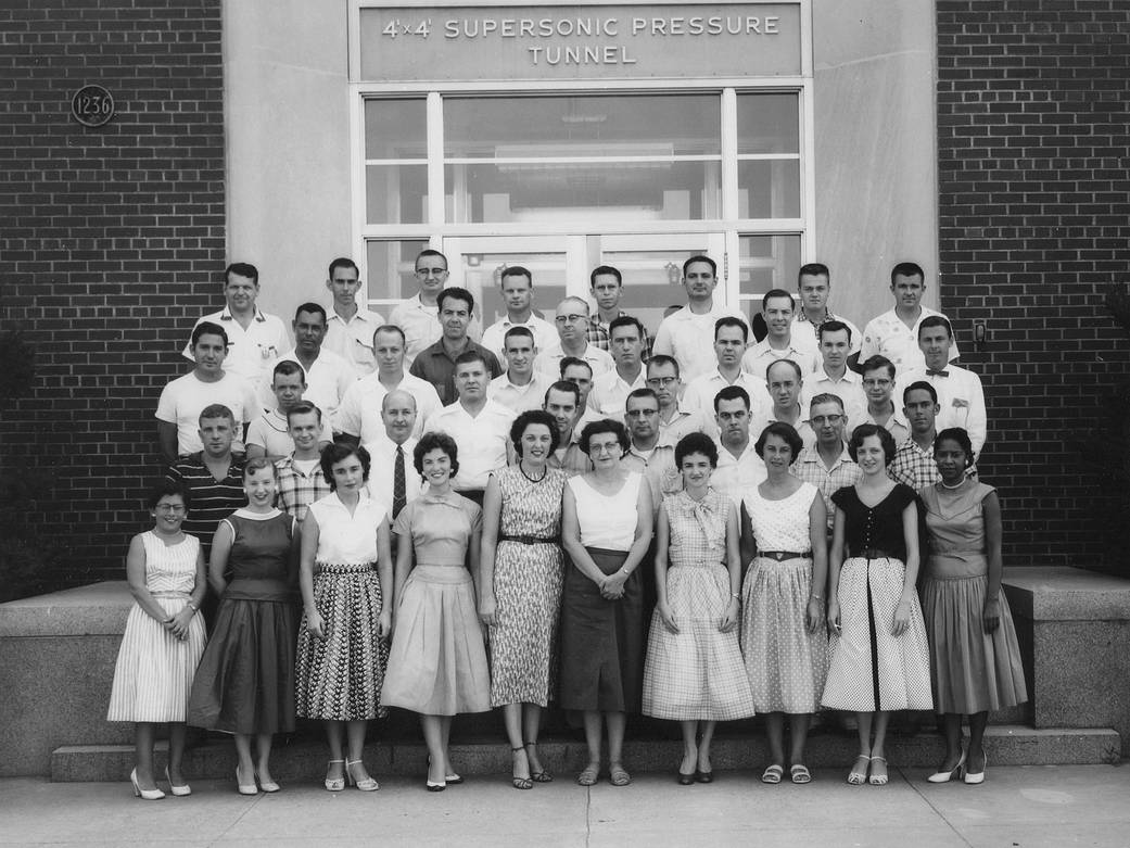 Black and white photograph of staff standing in front of supersonic pressure tunnel building