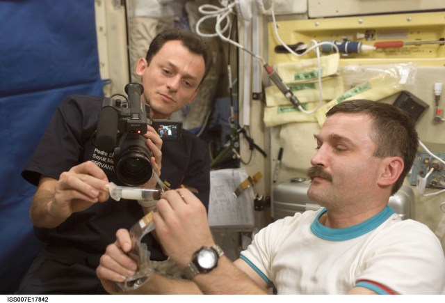 Astronauts work with a scientific experiment