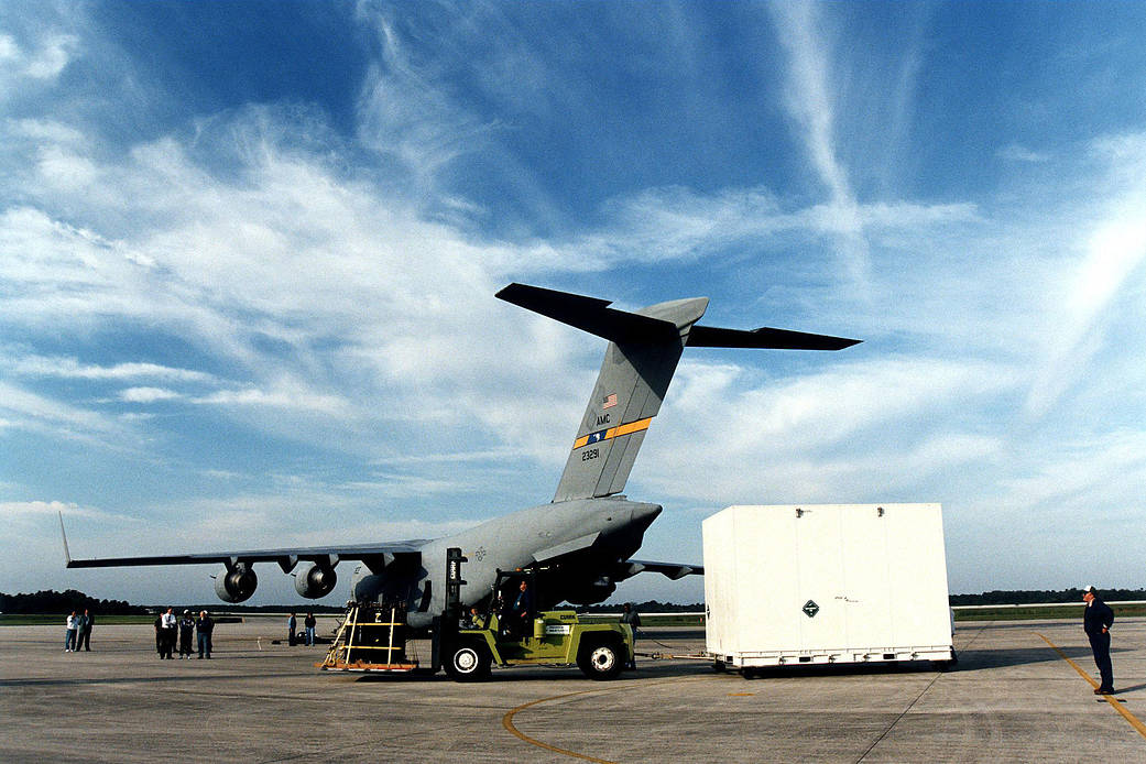 The shipping container carrying the Cassini orbiter is removed from the U.S. Air Force C-17 air cargo plane at Kennedy.