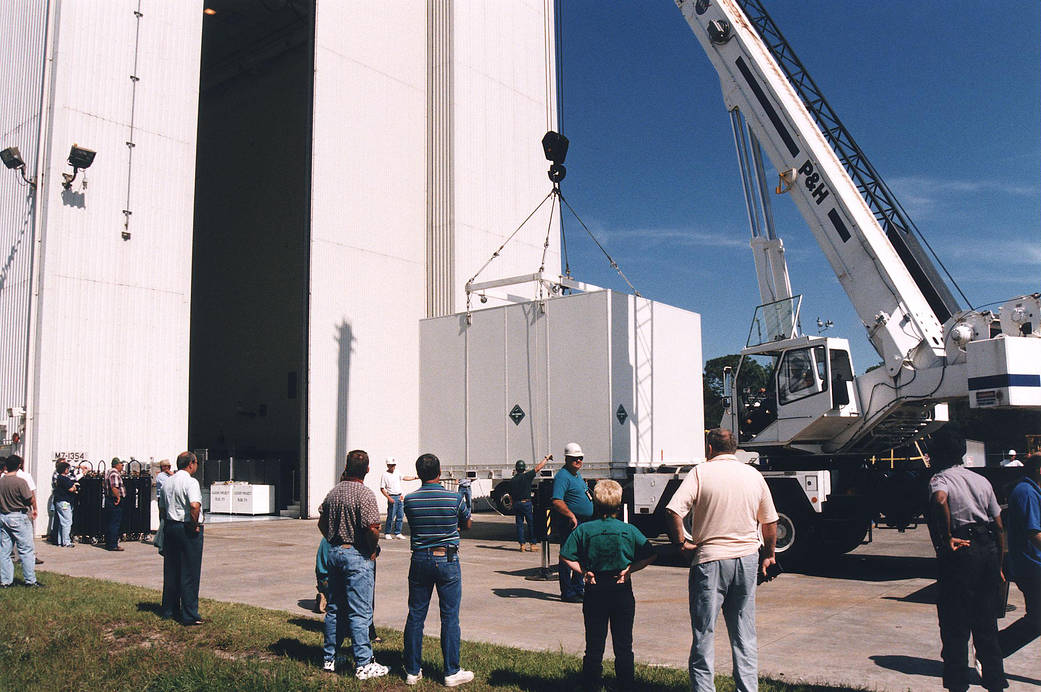 Workers prepare to move the shipping container with the Cassini orbiter inside the Payload Hazardous Servicing Facility.