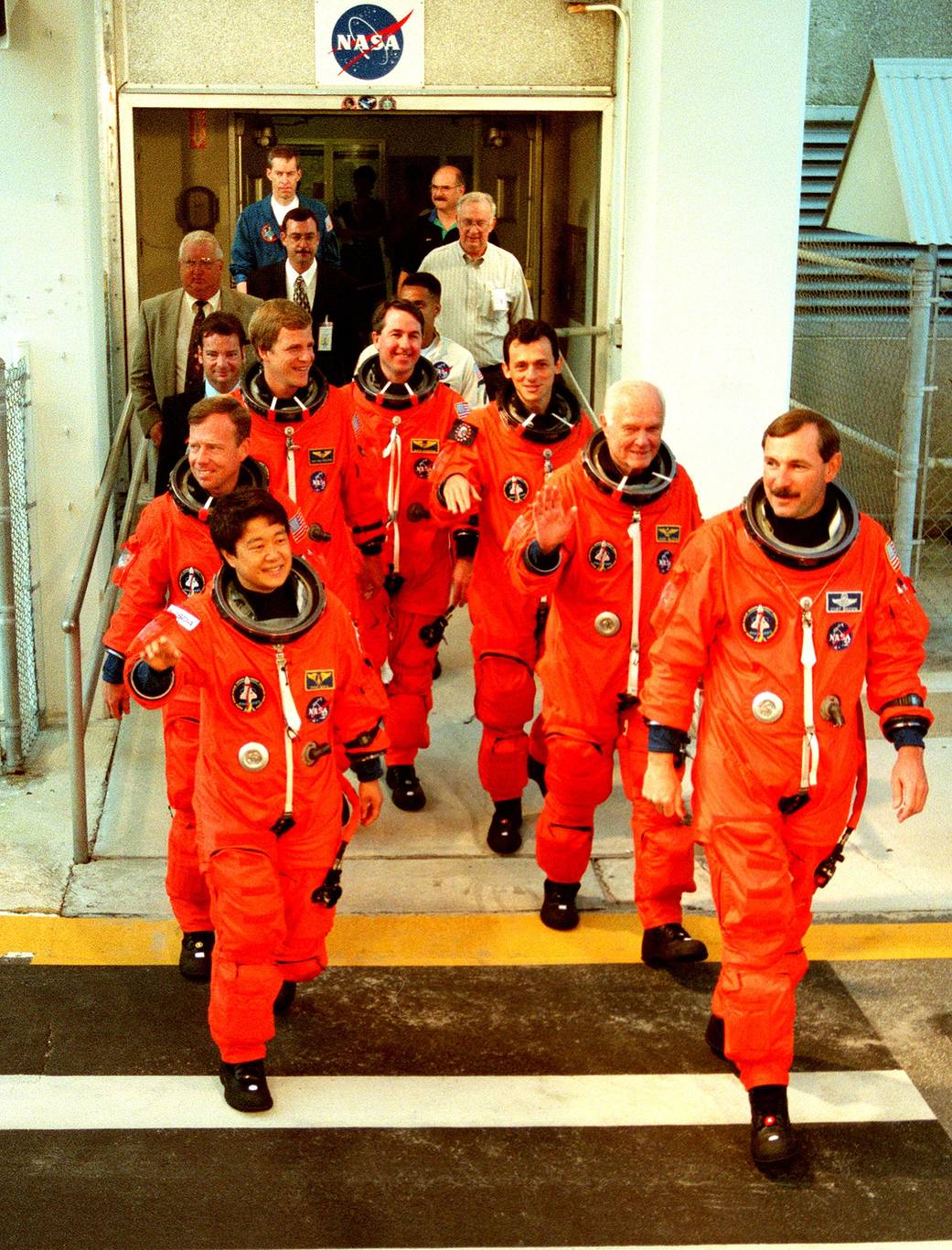 Shuttle crew members in orange suits exit building