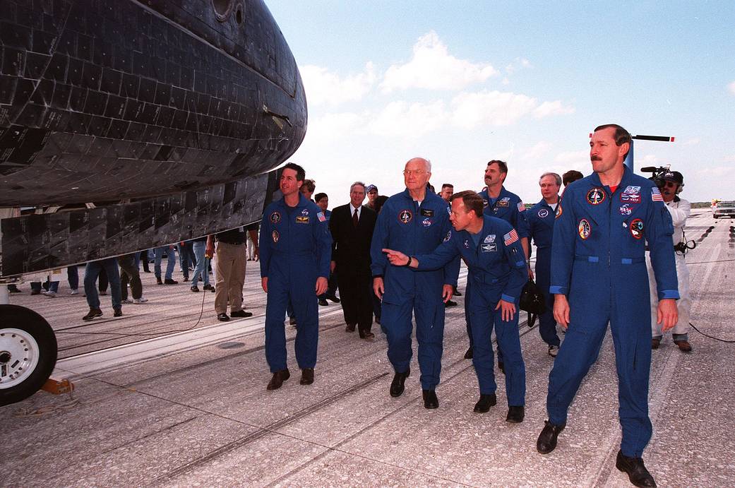 Shuttle crew in blue flight suits walks on tarmac