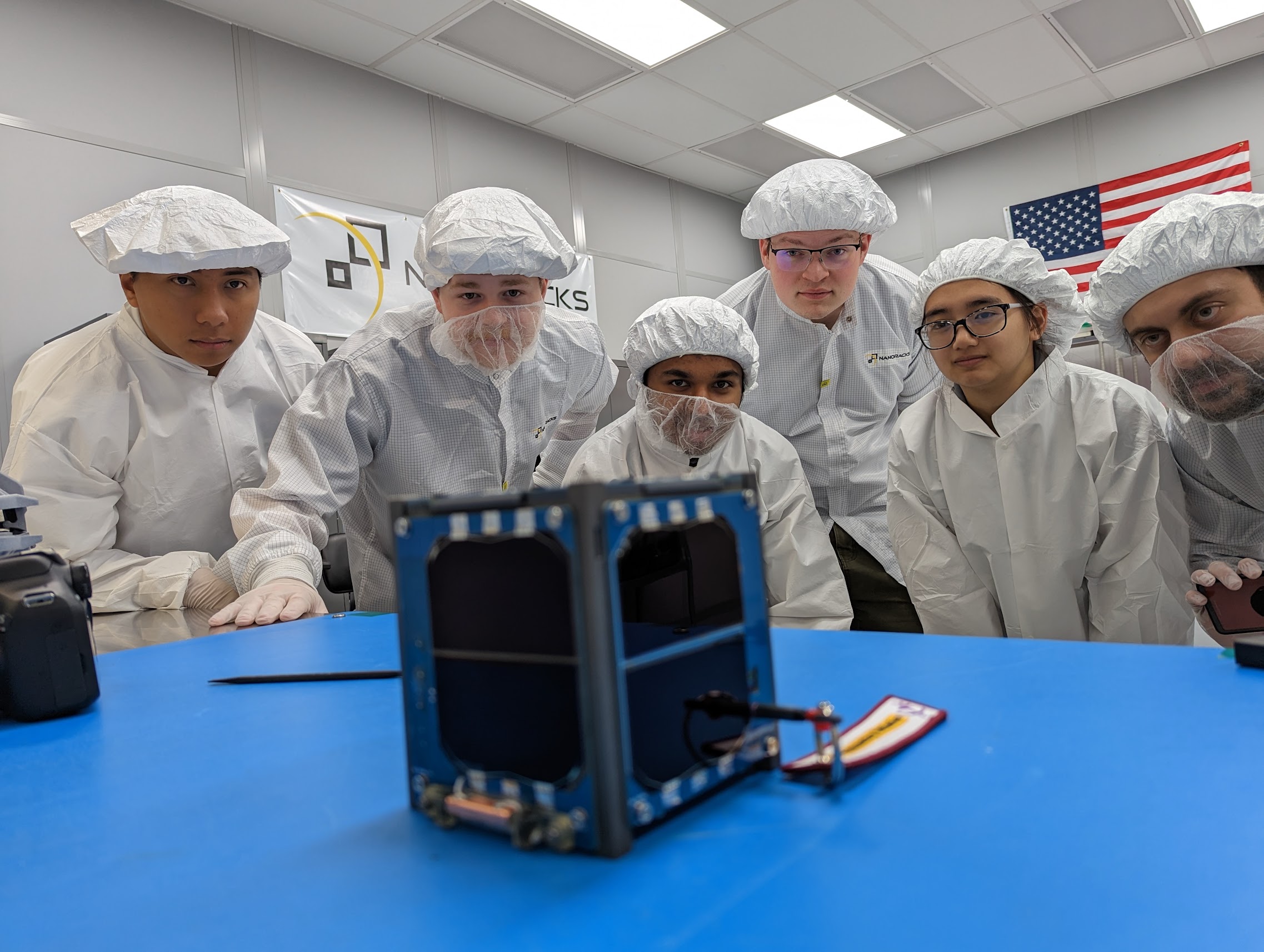 LightCube team members inspect the CubeSat prior to integration into the deployer. From left to right: David Ordaz Perez, Chandler Hutchens, Sam Cherian, Christopher McCormick, Ashley Lepham, Raymond Barakat.
