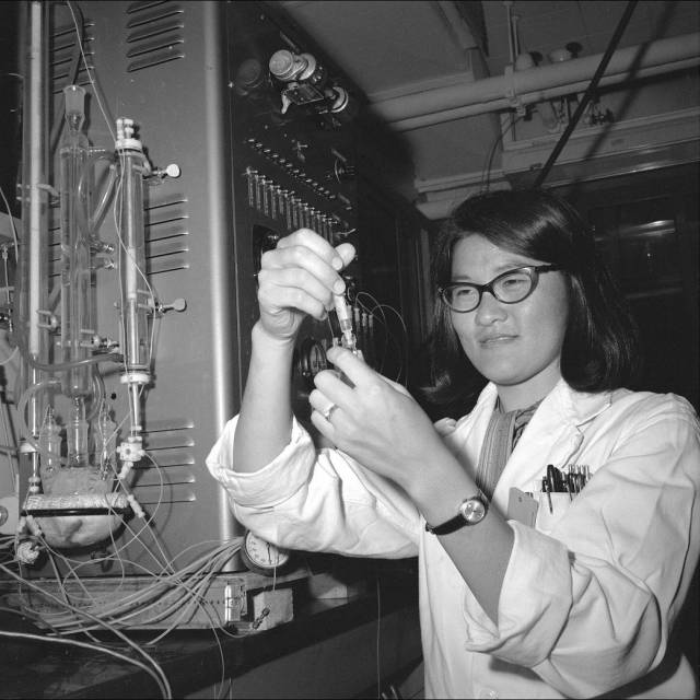 Chemist Audrey Miyamato holding a tube containing an Apollo lunar sample.