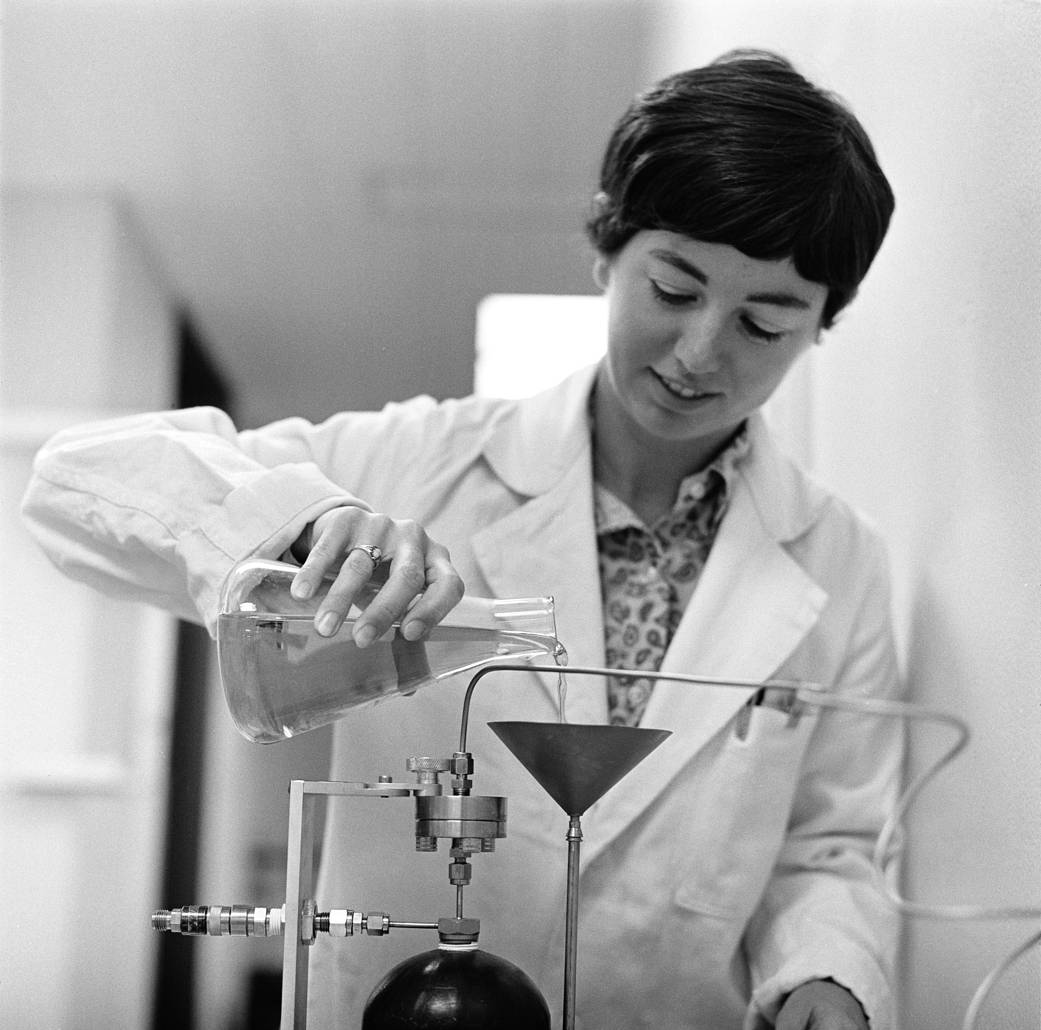 Biologist Caye Johnson pouring a liquid into a funnel.