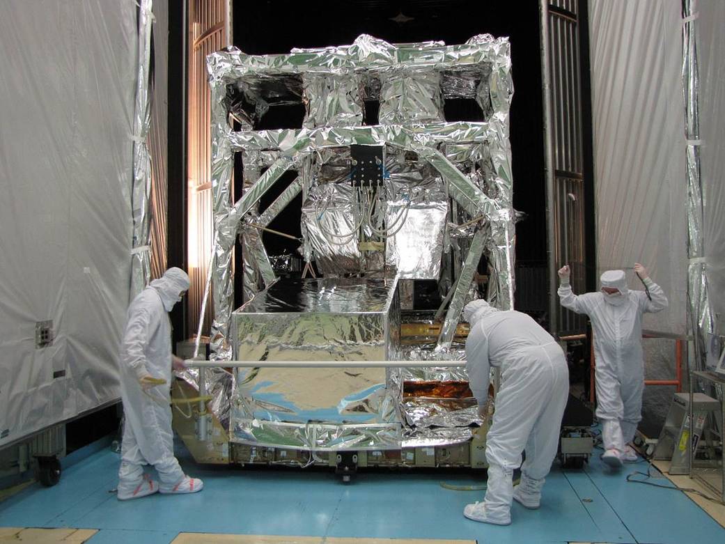 guys in coveralls work on a construction covered in shiny foil