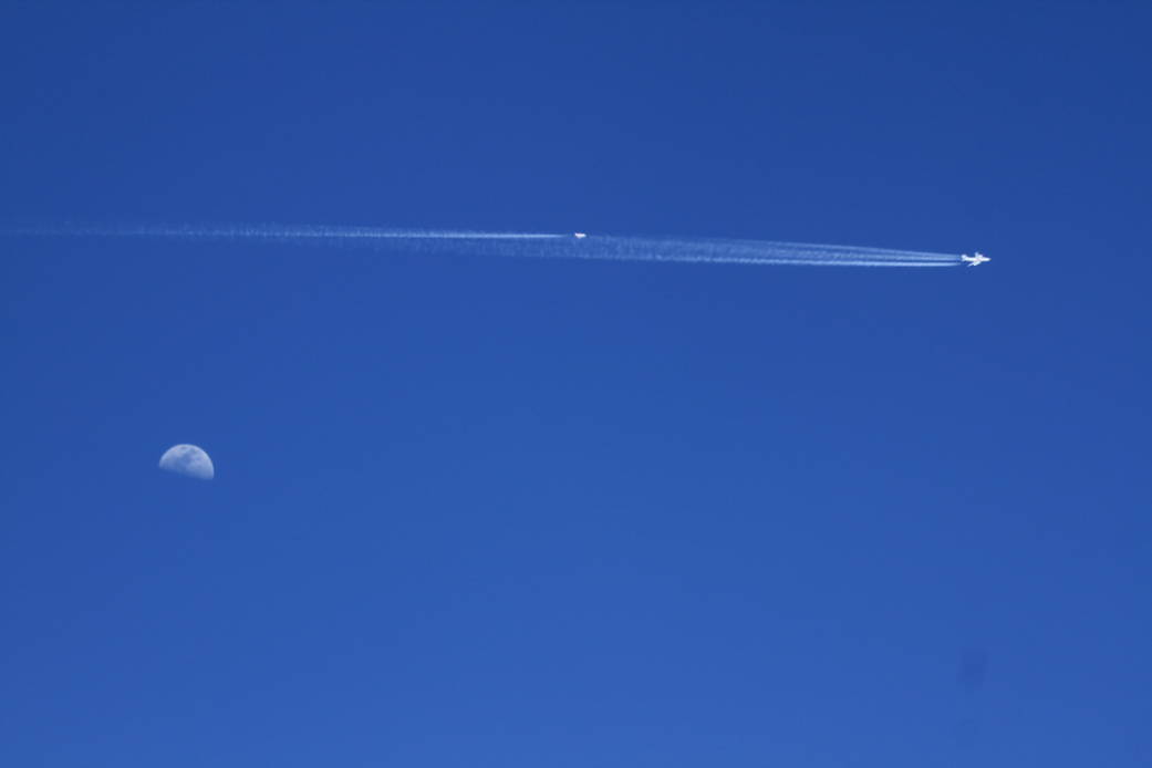 NASA's DC-8 leads one of the "sampling" chase aircraft across the morning clear blue sky with a shot of half the moon near NASA's Armstrong Aircraft Operations Facility