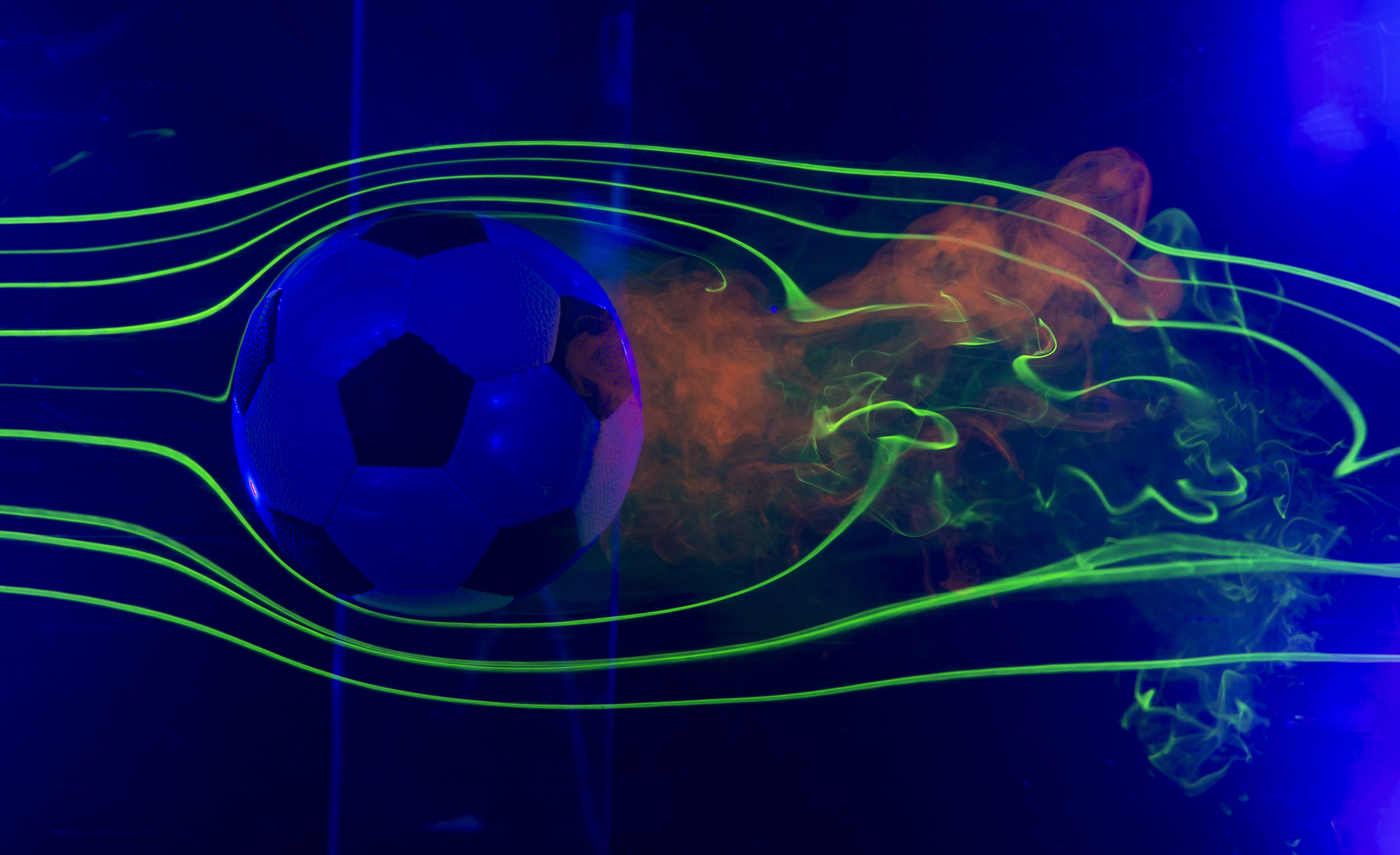 soccer ball in a water chamber with lasers and smoke around soccer ball