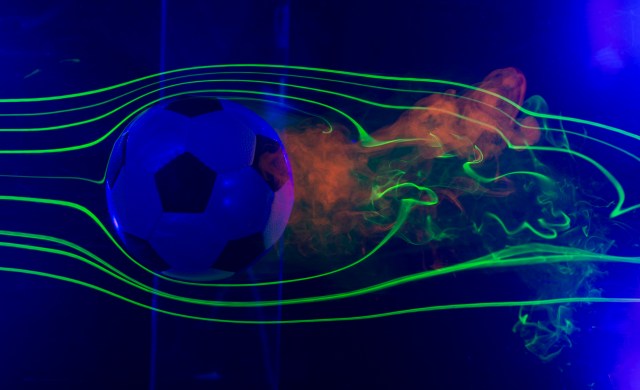 soccer ball in a water chamber with lasers and smoke around soccer ball