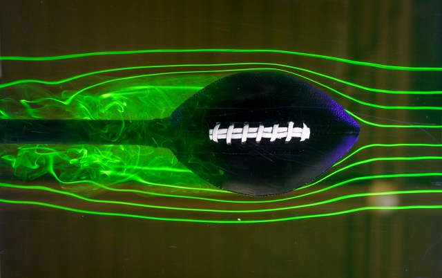 football in a water chamber with lasers and smoke around football