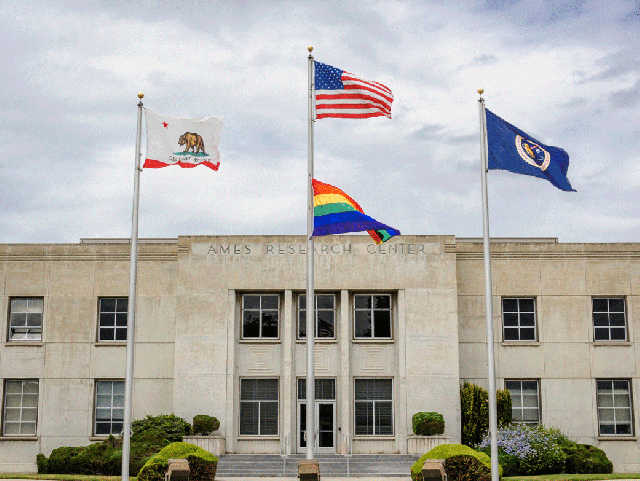 California, US, rainbow and NASA flags in front of the administration building at NASA's Ames Research Center.