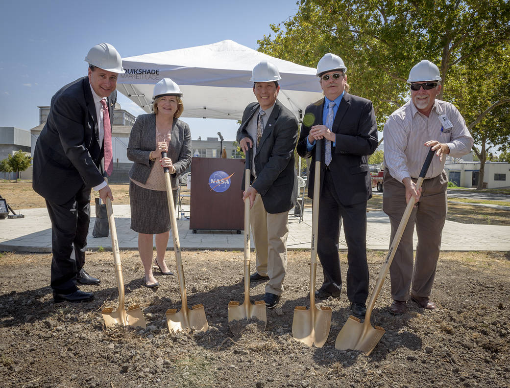 NASA officials place ceremonial golden shovels in the dirt for a building groundbreaking event.