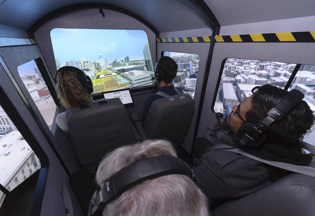 Four passengers look out the simulated windows of an air taxi cab inside the Vertical Motion Simulator