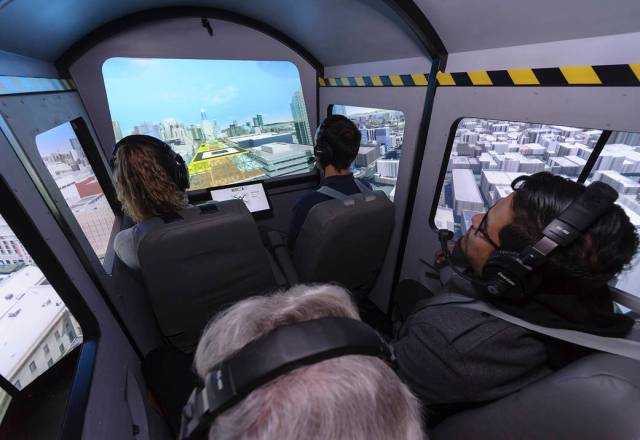 Four passengers look out the simulated windows of an air taxi cab inside the Vertical Motion Simulator.