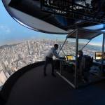 The people observe a large curved screen showing out the window views of San Francisco.