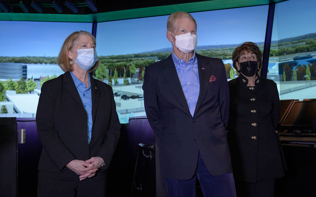 Three people view a panoramic city scene on three large monitors