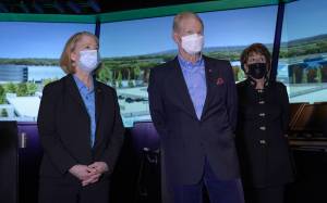 Three people view a panoramic city scene on three large monitors