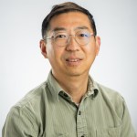 Portrait of Weile Wang in a green shirt and glasses.