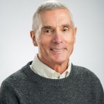 Portrait of Arthur Mizzi in a dark grey sweater and white collared shirt.