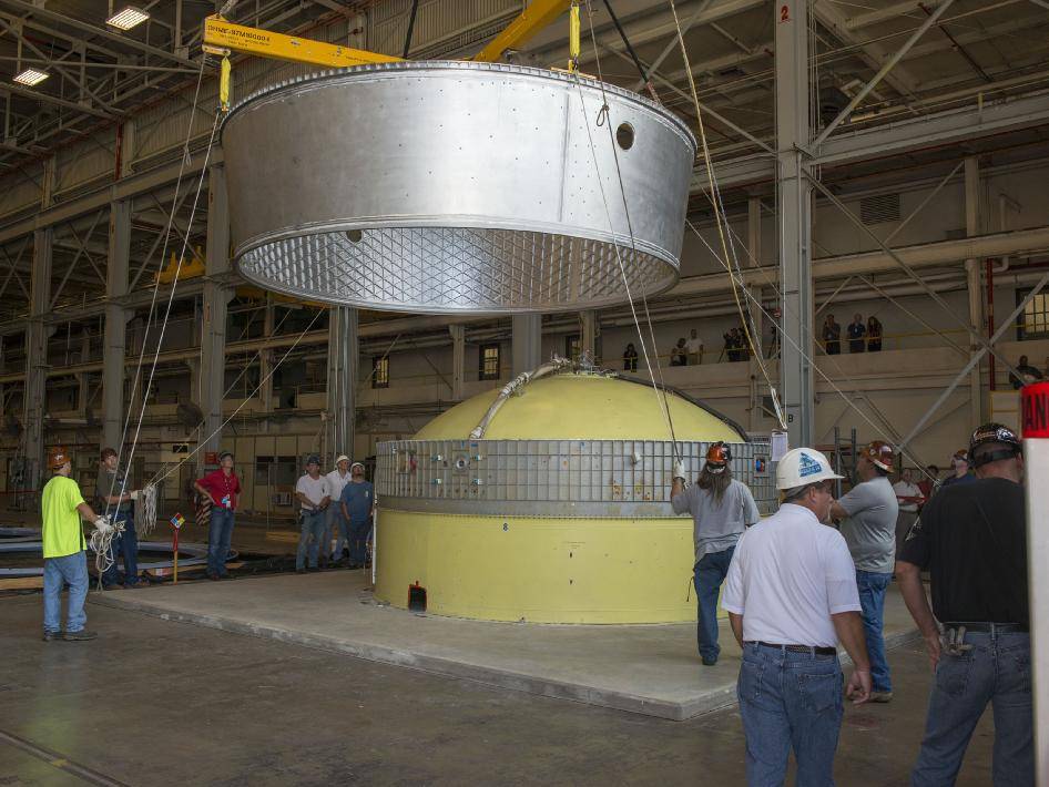 An adapter is lowered onto a ULA Delta IV test article for a fit check.