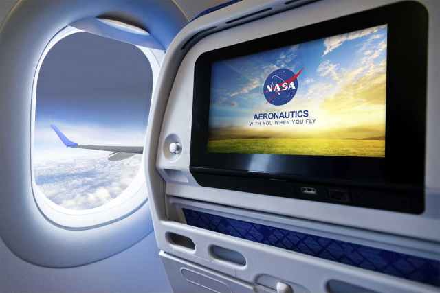 A graphic of a view from an airplane seat. The window is open and a cloudy sky and airplane wing are viewable. A TV monitor on the back of the headrest shows the NASA logo and the words, "Aeronautics NASA is with you when you fly,"