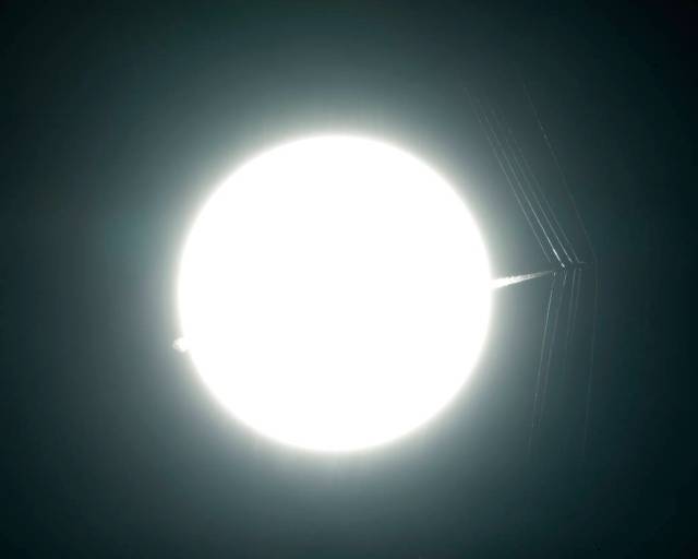 Bright sun with tip of aircraft passing in front at supersonic speed