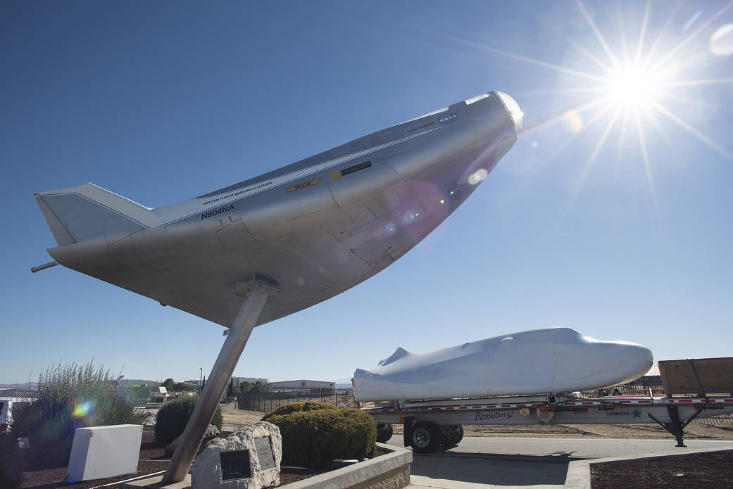 The Dream Chaser spacecraft on a truck bed, approaches the entrance to Armstrong Flight Research Center.