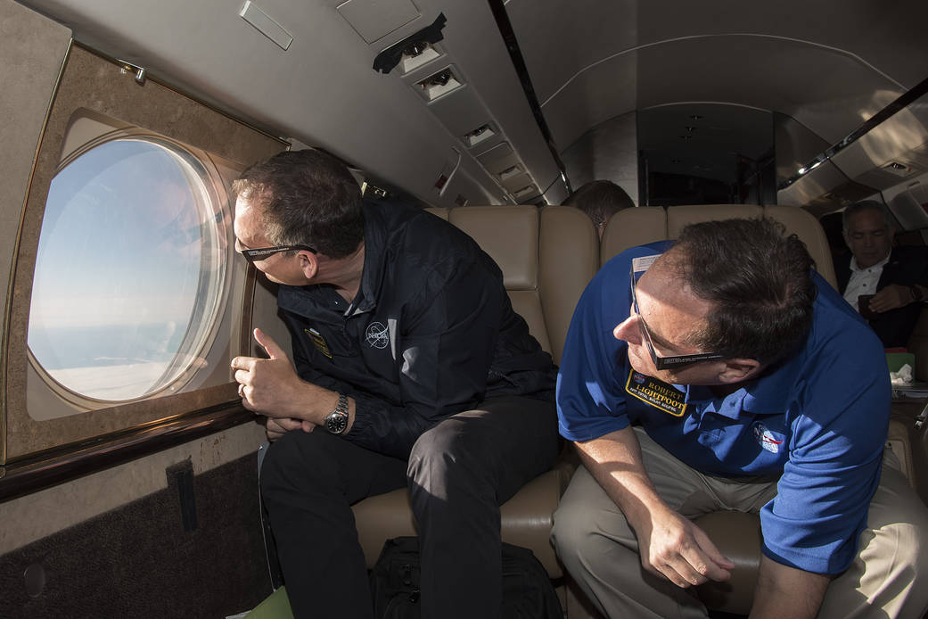 NASA officials look out window of aircraft
