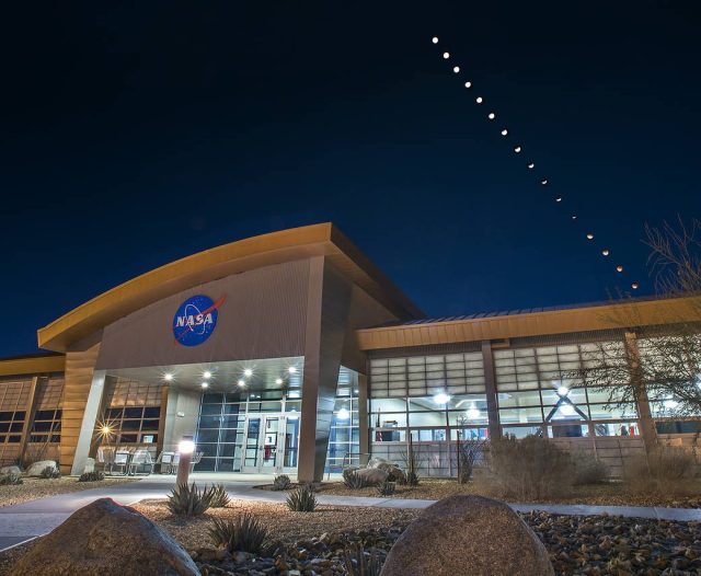 Armstrong Flight Research Center’s mission support building with a composite of 16 images of the eclipsed moons overhead 