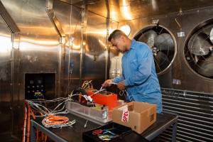 Angelo De La Rosa works inside the Environmental Laboratory’s thermal chamber to attach test articles.