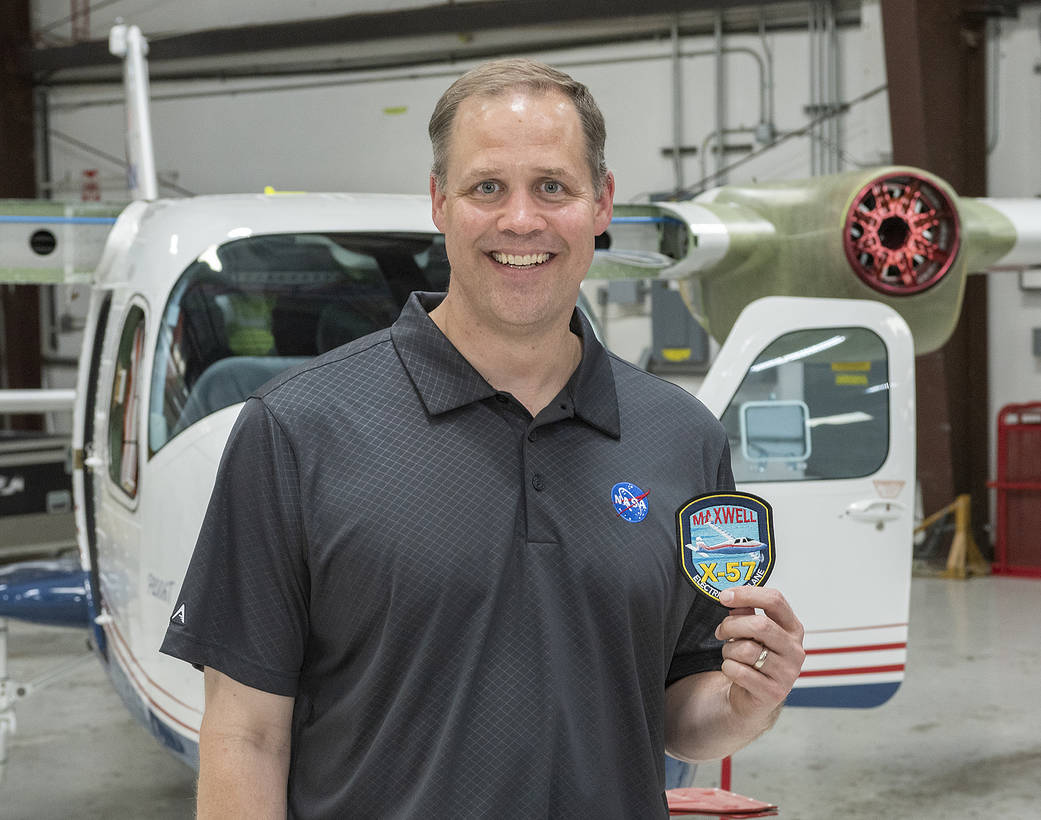 Administrator Bridenstine receives X-57 program patch standing in front of the X-57.