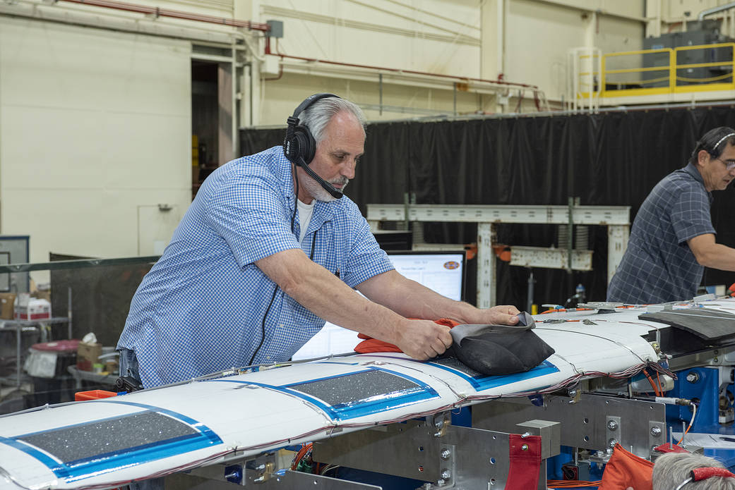 Technicians apply shot bags to the wing of the X-57 distributed electric aircraft wing.