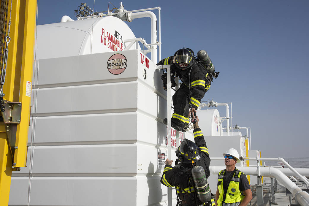 Air Force Plant 42 Fire Department responder Alfonzo Ortega, bottom, hands Doug Mendez a gas meter to test the air.