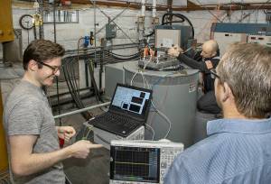 NASA engineer Jacob Terry, left, and Operations Manager Matthew Shemenski of Empirical Systems Aerospace (ESAero), right, prepare an X-57 cruise motor controller for vibration testing.