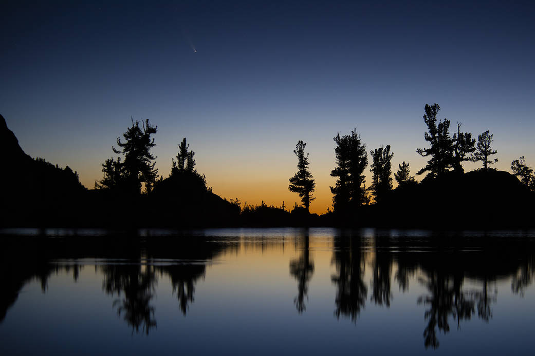 n image of the Comet C/2020 F3 NEOWISE (Comet NEOWISE) captured above the tree line of Lone Pine Lake.