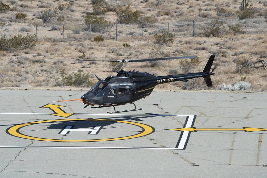Flight Research Inc.’s Bell OH-58C Kiowa helicopter hovering over a landing pad.