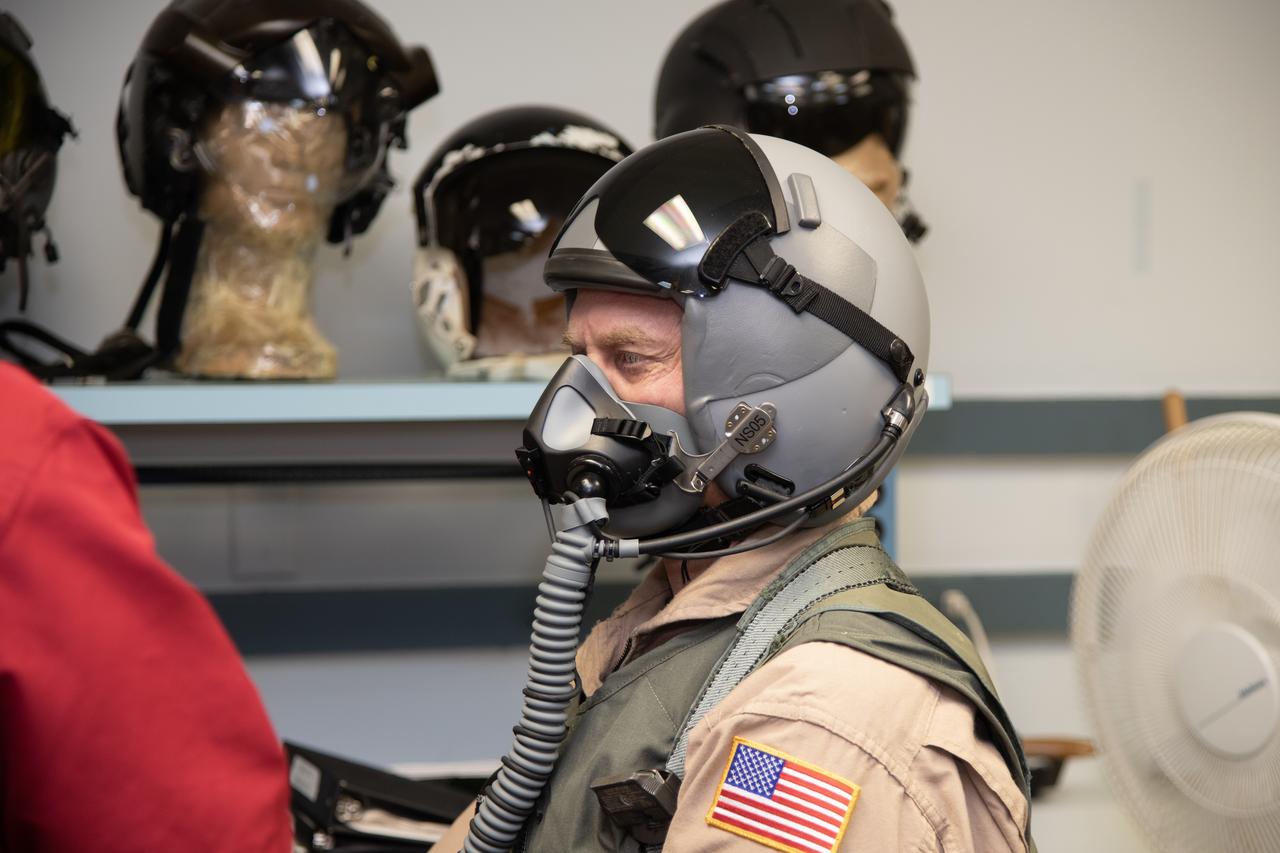 Man in flight helmet with attached breathing apparatus.