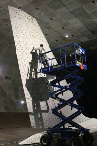 A man standing on a blue lift placing tiny jets called sweeping jet actuators on the full-sized tail from a 757 commercial aircraft.