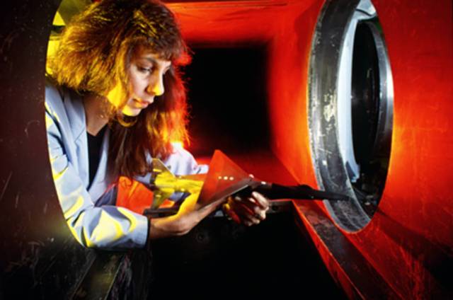 A female technician inspecting the model of the Hyper X mounted on a Pegasus booster rocket.