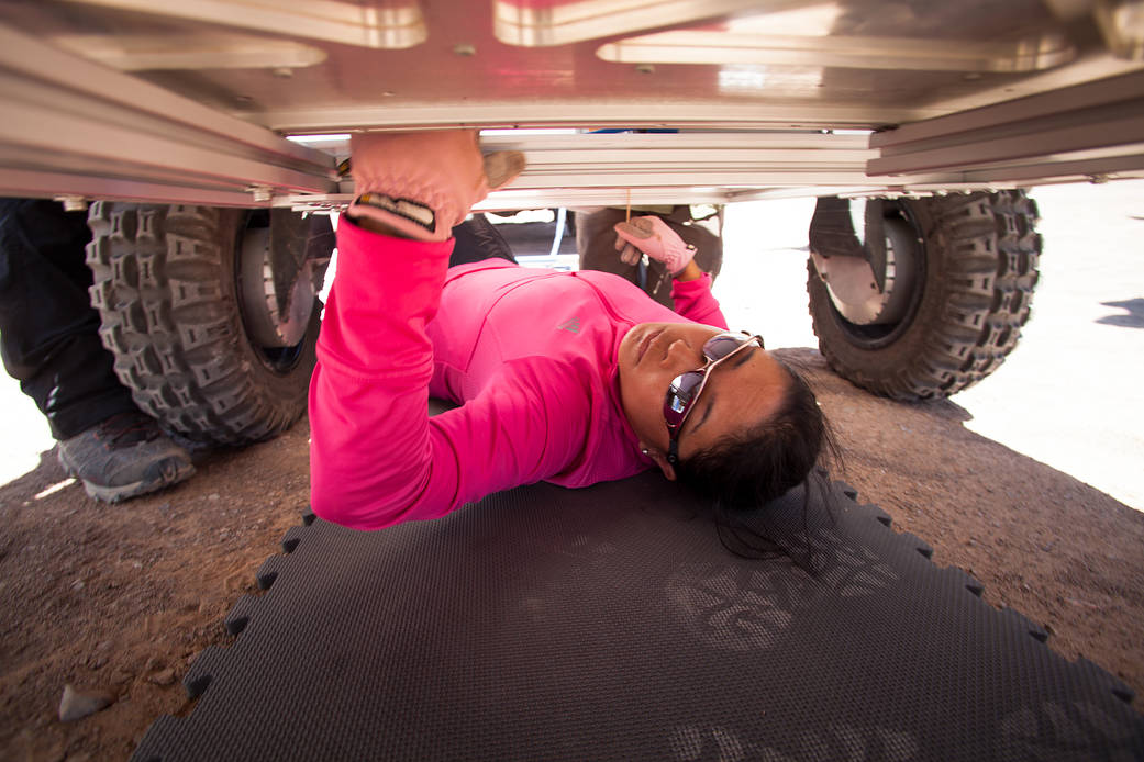 Linda Kobayashi, an electrical engineer on the ARADS team, helps install an instrument on the rover from below. 
